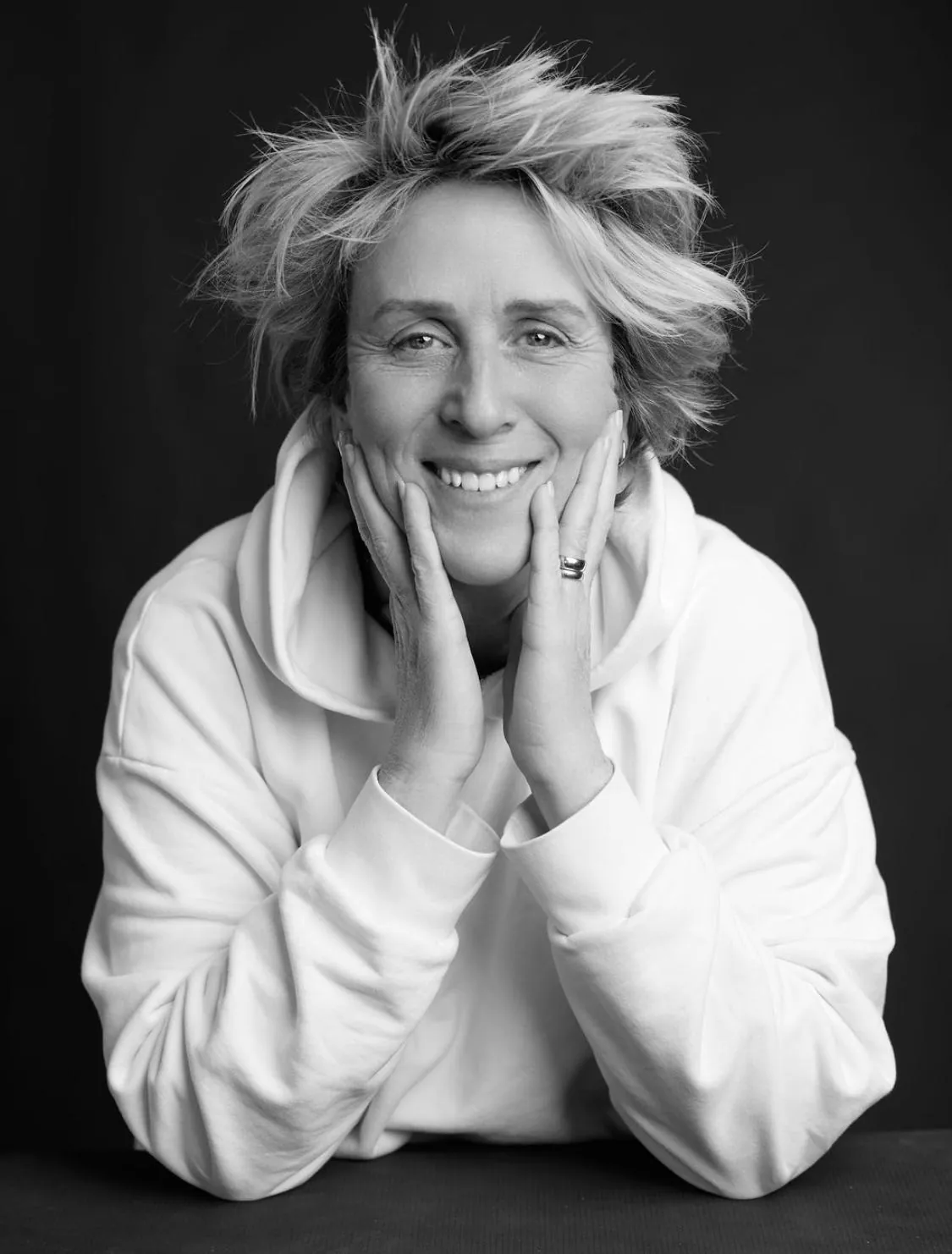 Black and white portrait of Stacey Key smiling with her hands against her cheeks